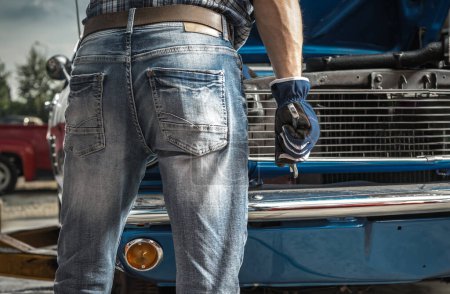Foto de Hombre caucásico trabajando en su coche clásico. Mantener la llave de hierro en sus manos de cerca. - Imagen libre de derechos