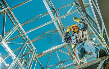 Foto de Trabajador del contratista de la construcción con la radio en sus manos que permanece en una estructura de acero del esqueleto - Imagen libre de derechos