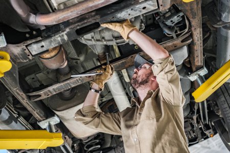 Photo for Professional Caucasian Car Mechanic Performing Undercarriage Repair - Royalty Free Image