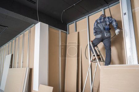 Foto de Contratista electricista Instalación de cable eléctrico mientras está de pie en una escalera. Tema de acabado de interiores. - Imagen libre de derechos