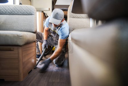 Foto de Caucasian Worker Vacuuming and Cleaning Rental RV Motor Home. Recreational Vehicle Maintenance Theme. - Imagen libre de derechos