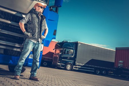 Kaukasischer europäischer Semi-Truck-Fahrer neben seinem blauen Semi-Truck. Trucker-Job Thema.