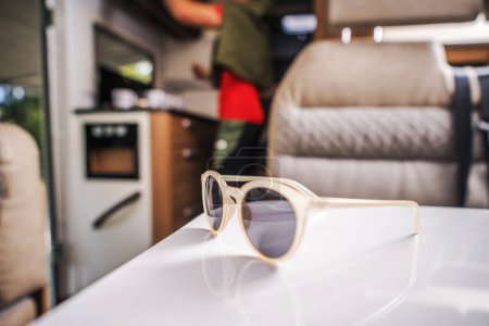 Photo for Sunglasses Left on a Table Inside Modern RV Camper Van. Vacation on the Road Theme. Recreational Vehicles. - Royalty Free Image