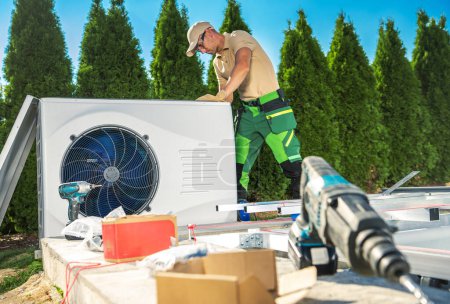 Photo for Caucasian HVAC Technician in His 40s Installing Modern Outdoor Heat Pump - Royalty Free Image