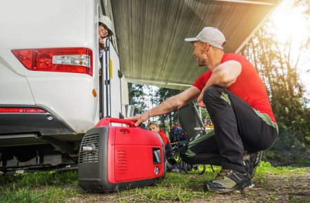 Man starting a generator in front of his RV while camping