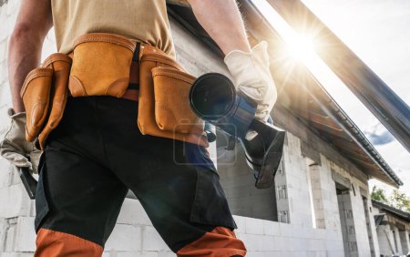 Photo for Construction worker wearing tool belt, holding piece of a gutter - Royalty Free Image