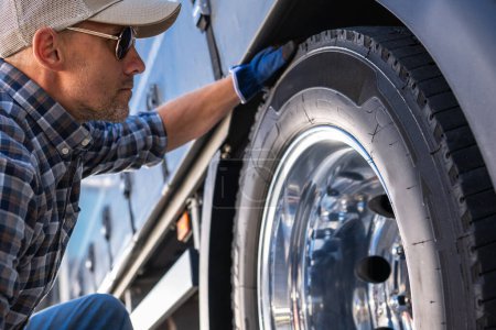 Photo for Caucasian professional trucker examining a tire on a truck. Close Up. Transportation Industry Theme. - Royalty Free Image