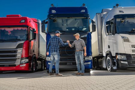 Téléchargez les photos : Deux chauffeurs semi-routiers caucasiens serrant la main devant un groupe de camions euro. - en image libre de droit