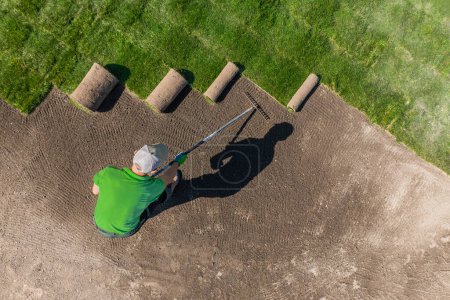 Téléchargez les photos : Vue aérienne d'un homme qui entretient un terrain de golf. Installation de nouveaux gazons d'herbe. - en image libre de droit