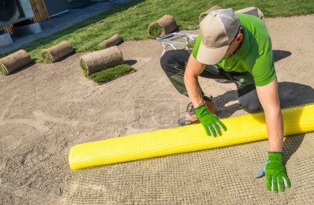 Photo for Caucasian Landscaper is spreading yellow professional mole repellent netting - Royalty Free Image
