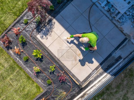 Photo for Homeowner cleans a patio from above. Backyard garden maintenance. - Royalty Free Image