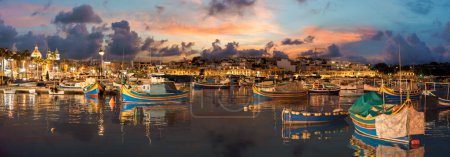 Foto de Landscape with traditional Luzzu boat in harbor of Marsaxlokk at night, Malta - Imagen libre de derechos
