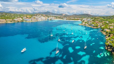 Captura aérea cautivadora de las aguas azules de Cala de Santa Ponca, con su extensa playa de arena y exuberantes alrededores, un remanso familiar tranquilo, Mallorca.