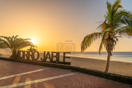 Téléchargez les photos : Masquer dans la chaude lueur du coucher de soleil à Morro Jable, Fuerteventura, où sable doré rencontrent les eaux tranquilles de l'Atlantique, rêve photographe - en image libre de droit