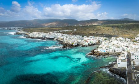 Explore Punta Mujeres in Lanzarote: a charming coastal village where crystal clear waters hug quaint white houses against a rugged landscape.