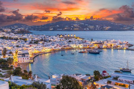 Genießen Sie die warmen Farben des Sonnenuntergangs in Mykonos-Stadt Chora, wo das azurblaue Wasser der Ägäis das pulsierende Leben dieser ikonischen griechischen Insel widerspiegelt.