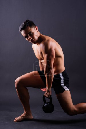 Foto de Handsome muscular man holding a kettle bell with copy space. Hispanic male athlete - Imagen libre de derechos