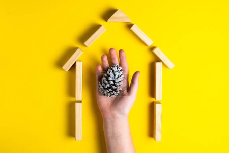Photo for Cone with kids hand. House from wooden blocks. Close up. Top view. - Royalty Free Image