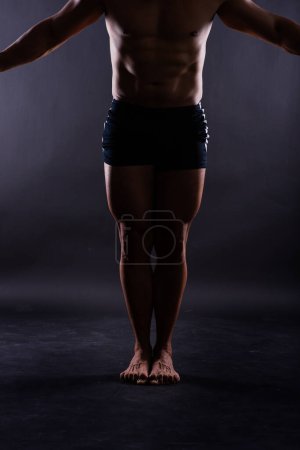 Téléchargez les photos : Muscular male legs close up studio shot on dark background - en image libre de droit