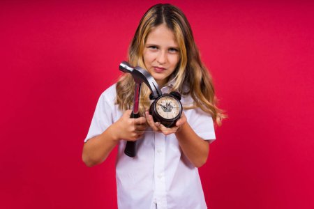 Photo for Young blonde girl holding an alarm clock and hammer smiling and laughing hard out loud. - Royalty Free Image