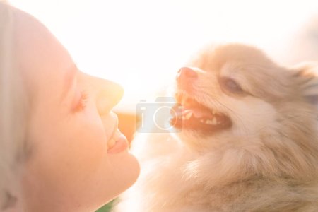 Close up portrait of smiling young attractive woman embracing Pomeranian spitz.