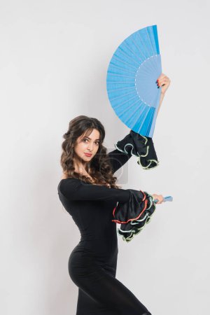 Portrait of beautiful young woman dancing flamenco with fan in studio