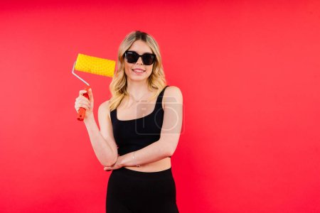 Téléchargez les photos : Jeune femme avec brosse à rouleaux sur fond blanc rouge Instruments accessoires pour salle de rénovation - en image libre de droit