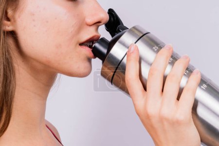 Téléchargez les photos : Vue latérale rapprochée d'une femme sportive après l'entraînement qui boit de l'eau fraîche provenant d'une bouteille de sport - en image libre de droit