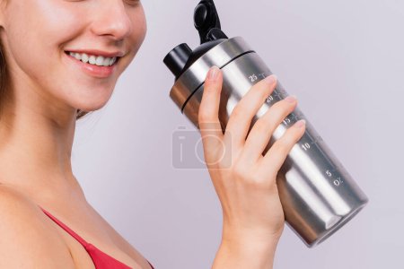 Téléchargez les photos : Vue latérale rapprochée d'une femme sportive après l'entraînement qui boit de l'eau fraîche provenant d'une bouteille de sport - en image libre de droit