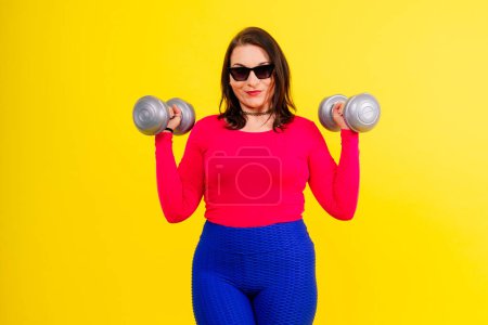 Photo for Sporty plump woman doing an exercises with dumbbells. Sports motivation and healthy lifestyle - Royalty Free Image