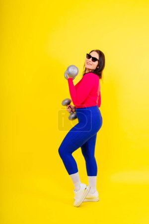 Photo for Sporty plump woman doing an exercises with dumbbells. Sports motivation and healthy lifestyle - Royalty Free Image