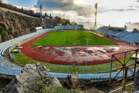 Photo for City of Rijeka, Croatia, Jan 25 2023, View of the unique stadium of football club Rijeka, near the Adriatic sea in the morning sky. The Kantrida stadium is located between a large rock and the sea. Backlit view - Royalty Free Image