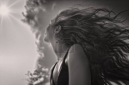Photo for Close-up of a girl with long hair portrayed from below with the sky as the background - Royalty Free Image