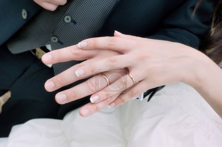 Photo for The bride's hand resting on top of the groom's hand, with the wedding rings in the foreground - Royalty Free Image