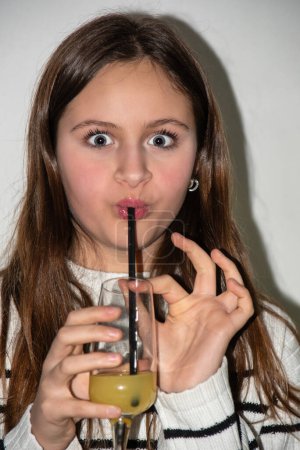 Junges Teenager-Mädchen macht ein komisches Gesicht, während es einen Cocktail trinkt