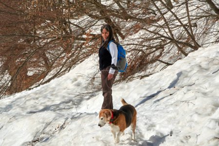  Dame avec un chien Beagle lors d'une randonnée dans la neige dans les montagnes