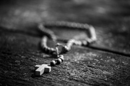 Rosaire sur une vieille table en bois éclairée par le soleil. La scène représente la dévotion dans la prière et une nouvelle espérance