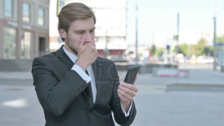 Foto de Upset Middle Aged Businessman Reacting to Loss on Smartphone Outdoor - Imagen libre de derechos