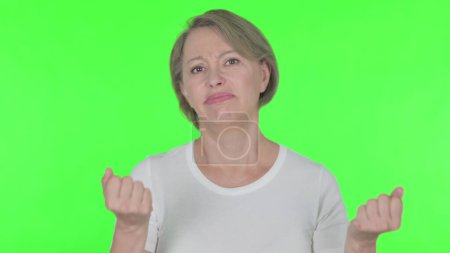 Foto de Disappointed Senior Old Woman Reacting Loss on Green Background - Imagen libre de derechos