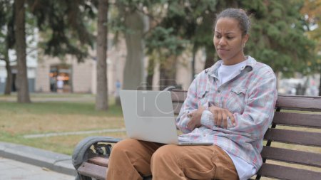 Foto de Young African Woman Reacting to Loss on Laptop while Sitting Outdoor on Bench - Imagen libre de derechos