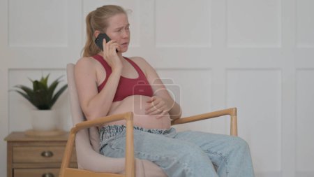 Photo for Angry Pregnant Woman Talking on Phone at Home - Royalty Free Image