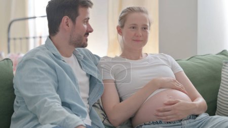 Foto de Talking Pregnant Couple Relaxing at Home, Discussing Future - Imagen libre de derechos