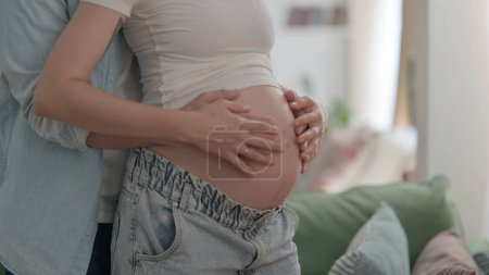 Foto de Male Hands Holding Pregnant Woman Big Belly - Imagen libre de derechos
