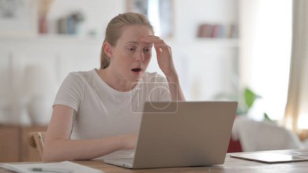 Foto de Mujer joven reaccionando a la pérdida mientras usa el ordenador portátil - Imagen libre de derechos