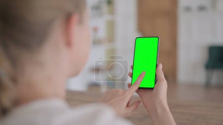 Photo for Rear View of Young Woman Looking at Smartphone with Green Chroma Screen - Royalty Free Image