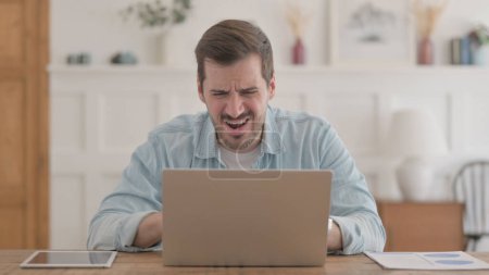 Photo for Casual Young Man Reacting to Loss While using Laptop - Royalty Free Image