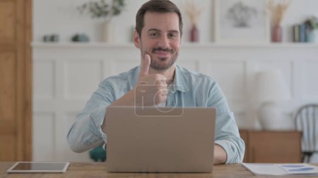 Photo for Casual Man Showing Thumbs Up While using Laptop - Royalty Free Image