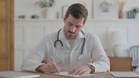 Téléchargez les photos : Male Doctor Writing on Paper in Clinic, Medical Report - en image libre de droit