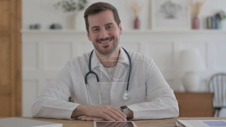 Téléchargez les photos : Male Doctor Smiling at Camera While sitting in Clinic - en image libre de droit