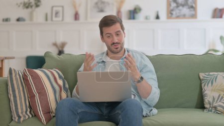 Photo for Casual Man doing Video Call on Laptop on Sofa - Royalty Free Image